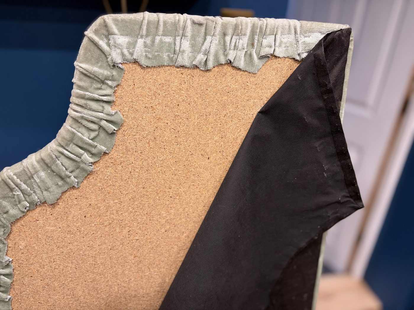 Close-up of the original headboard fabric, worn and torn at the corner