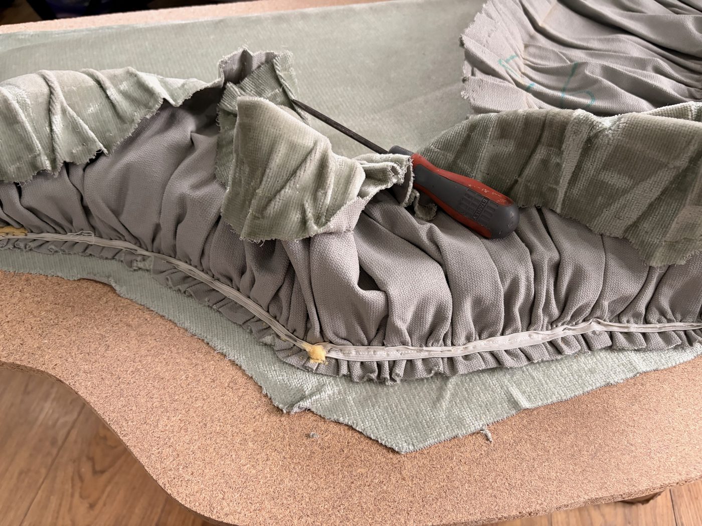 The headboard stripped back to its board with the old fabric loosened